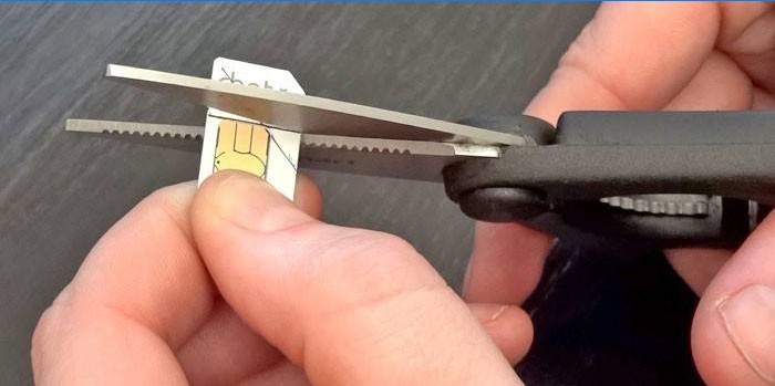 Um homem corta um cartão SIM de acordo com o padrão com uma tesoura