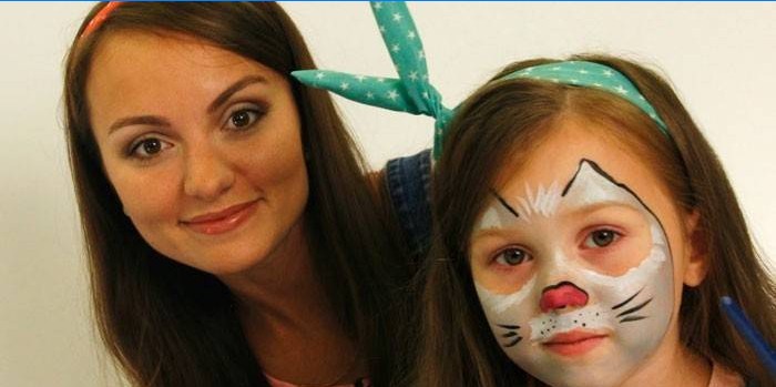 Menina com pintura de rosto de gato e mãe