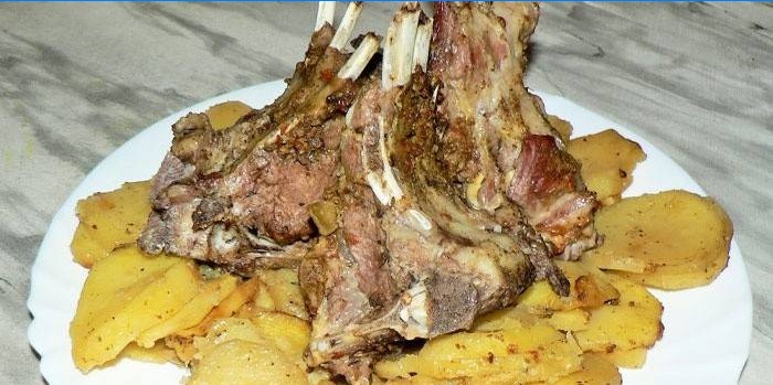 Prato com costelas de cordeiro assadas em um travesseiro de batatas