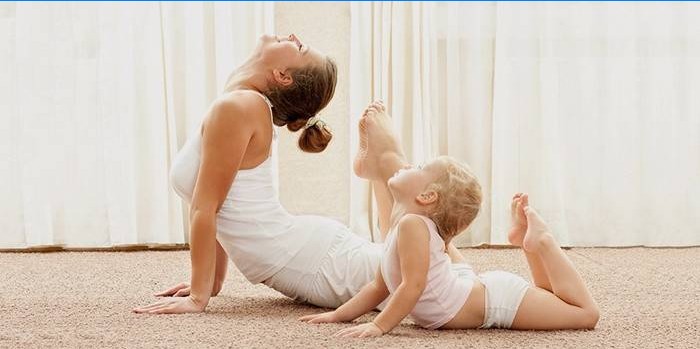 Mãe e bebê fazem yoga em casa.