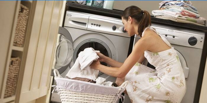 Garota coloca toalhas em uma máquina de lavar
