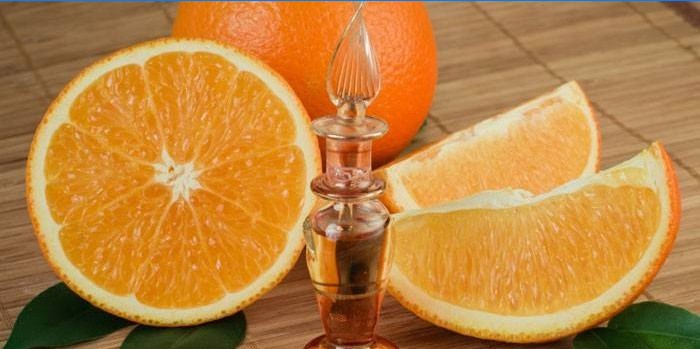 Óleo essencial de laranja em uma garrafa e laranja picada
