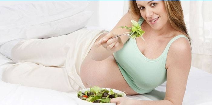 Menina grávida comendo salada