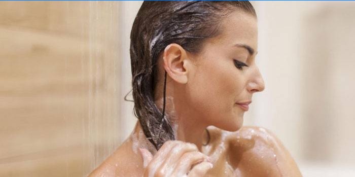 Menina lava o cabelo no chuveiro