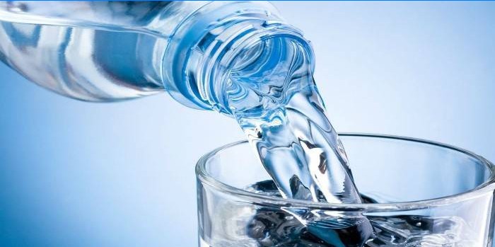 Água de uma garrafa é despejada em um copo
