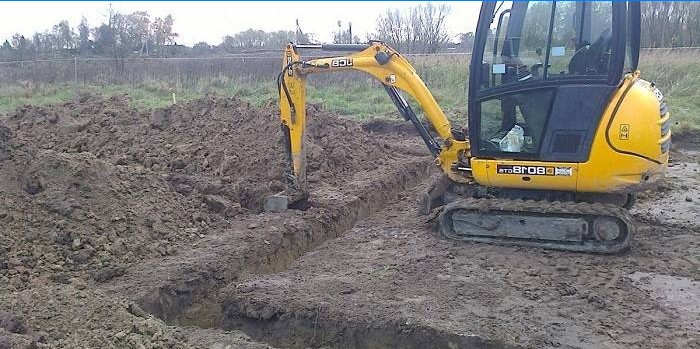 Escavadeira cava trincheiras no local