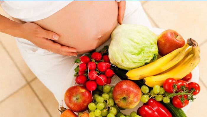 Mulher grávida com legumes e frutas