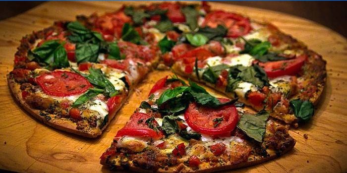 Pizza fina com recheio de tomate e mussarela e manjericão