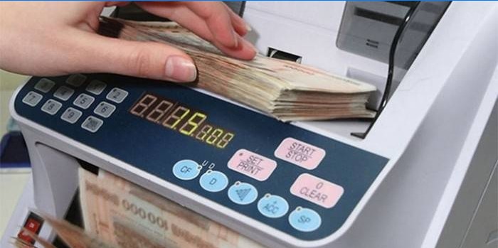 Mulher conta dinheiro com uma máquina de notas