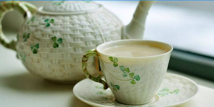 Chá verde com leite em uma xícara e bule