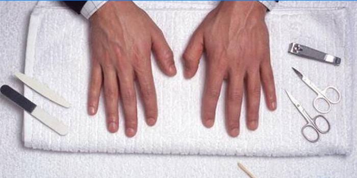 Mãos de um homem após manicure e kit de ferramentas